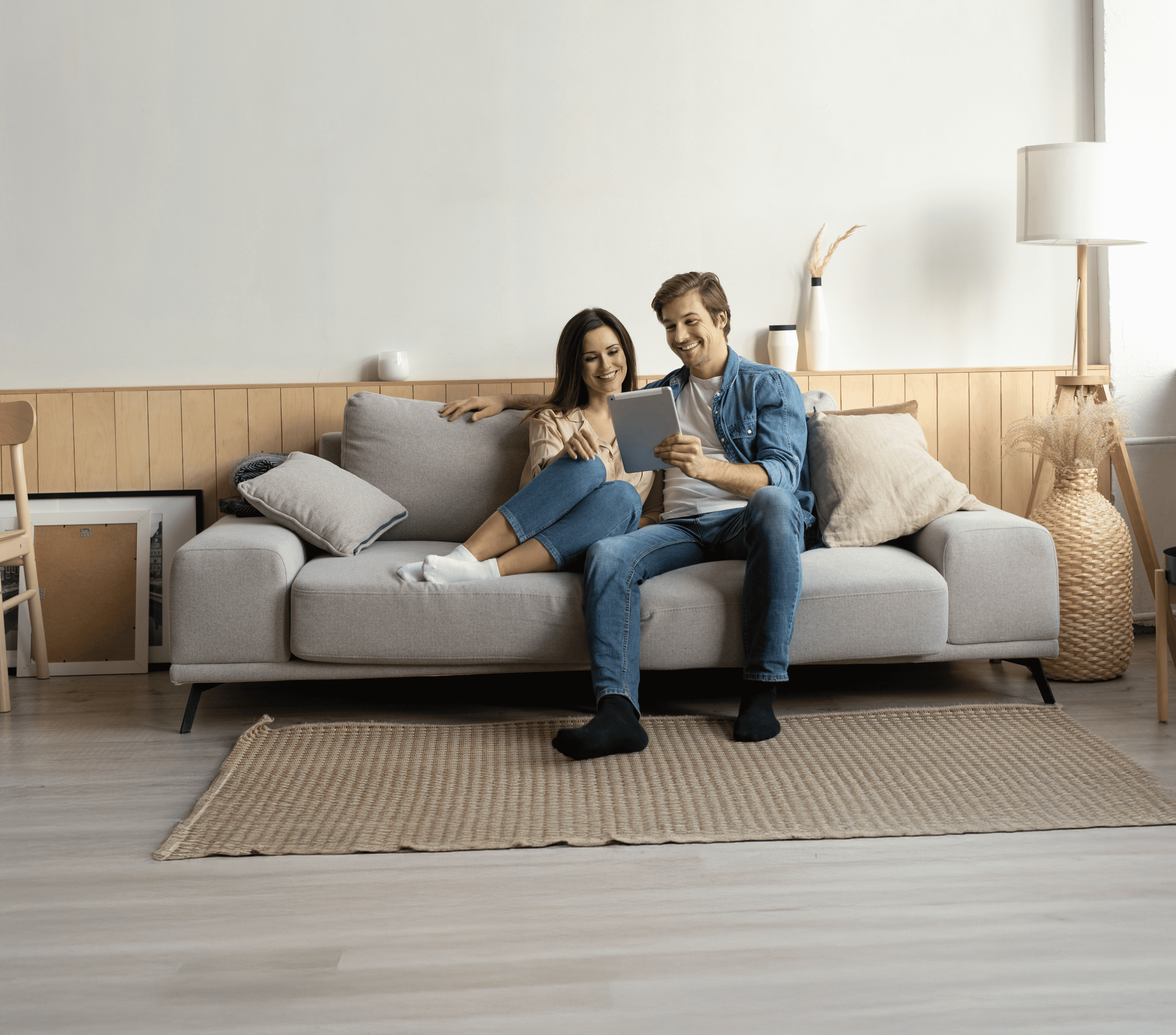 Couple sitting on the couch looking at a tablet.